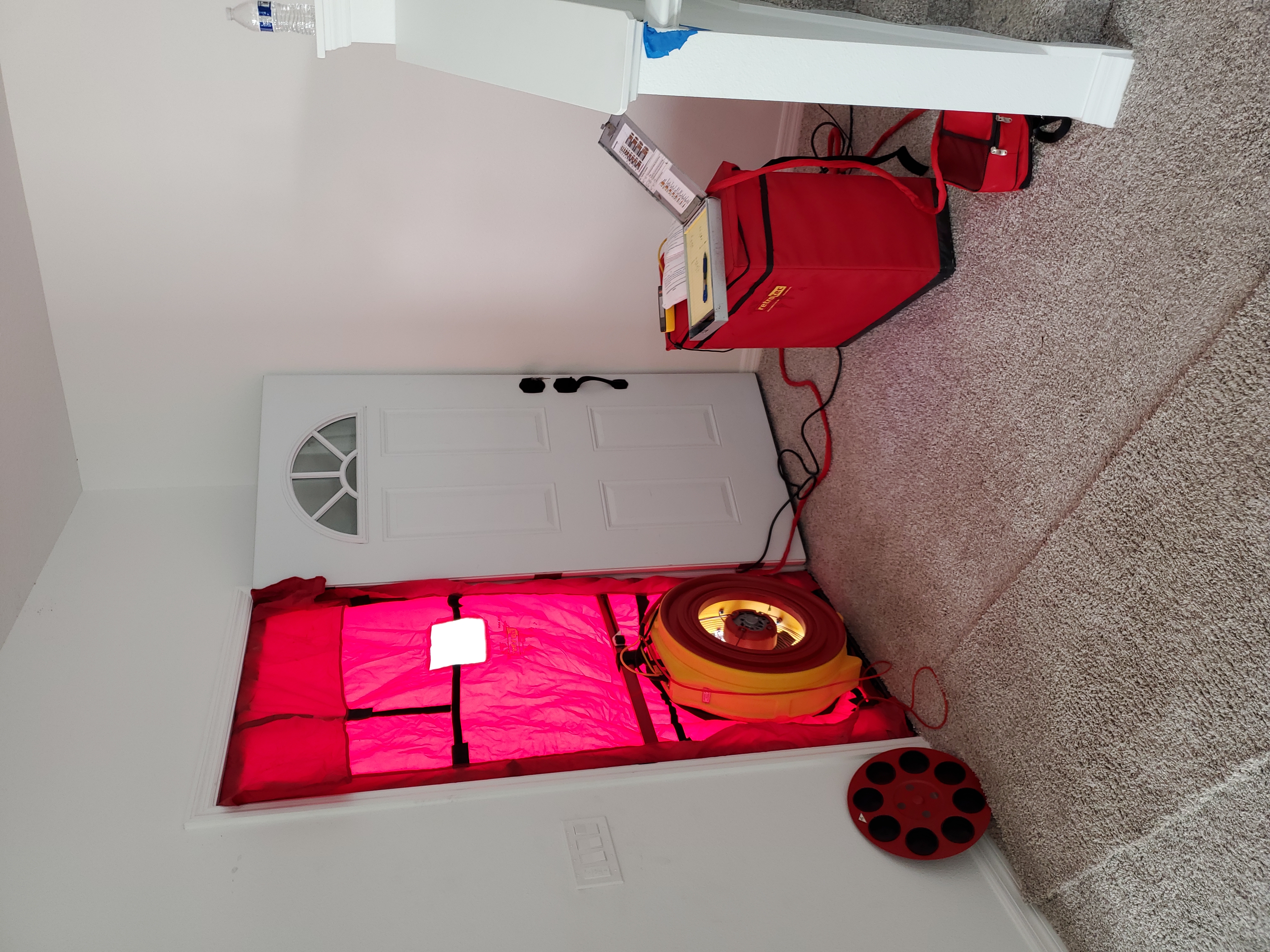Blower door test with red panel and fan installed in residential doorway