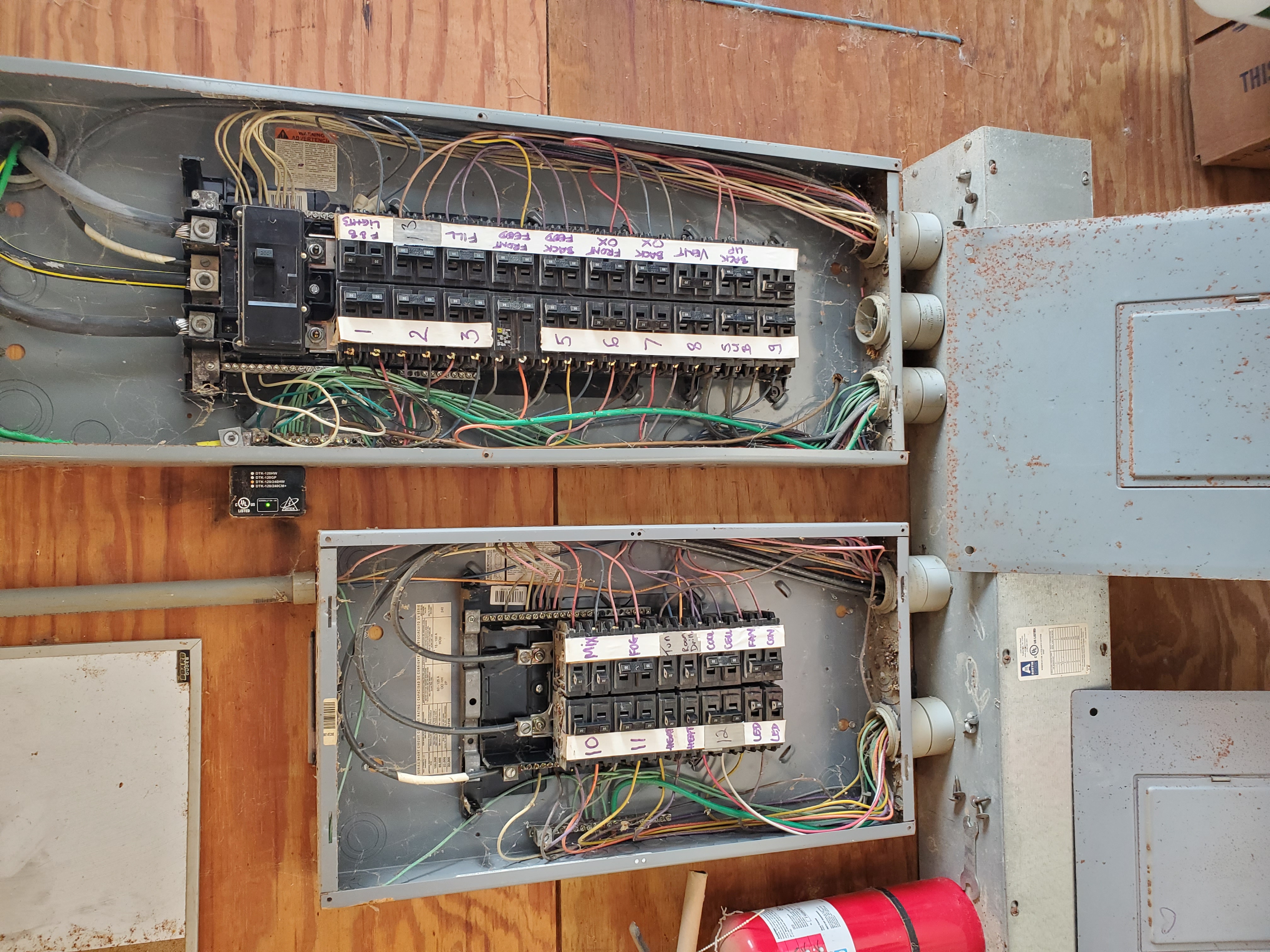 Open breaker panels with hand-labeled circuits during inspection